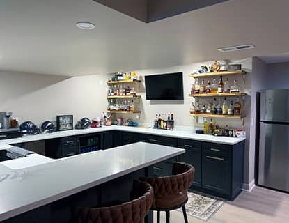 Custom basement bar with navy cabinetry and floating shelves in Plain City, OH
